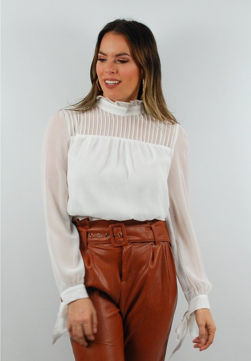 Blusa blanca con pliegues, mangas con lazos en los puños y escote con abertura