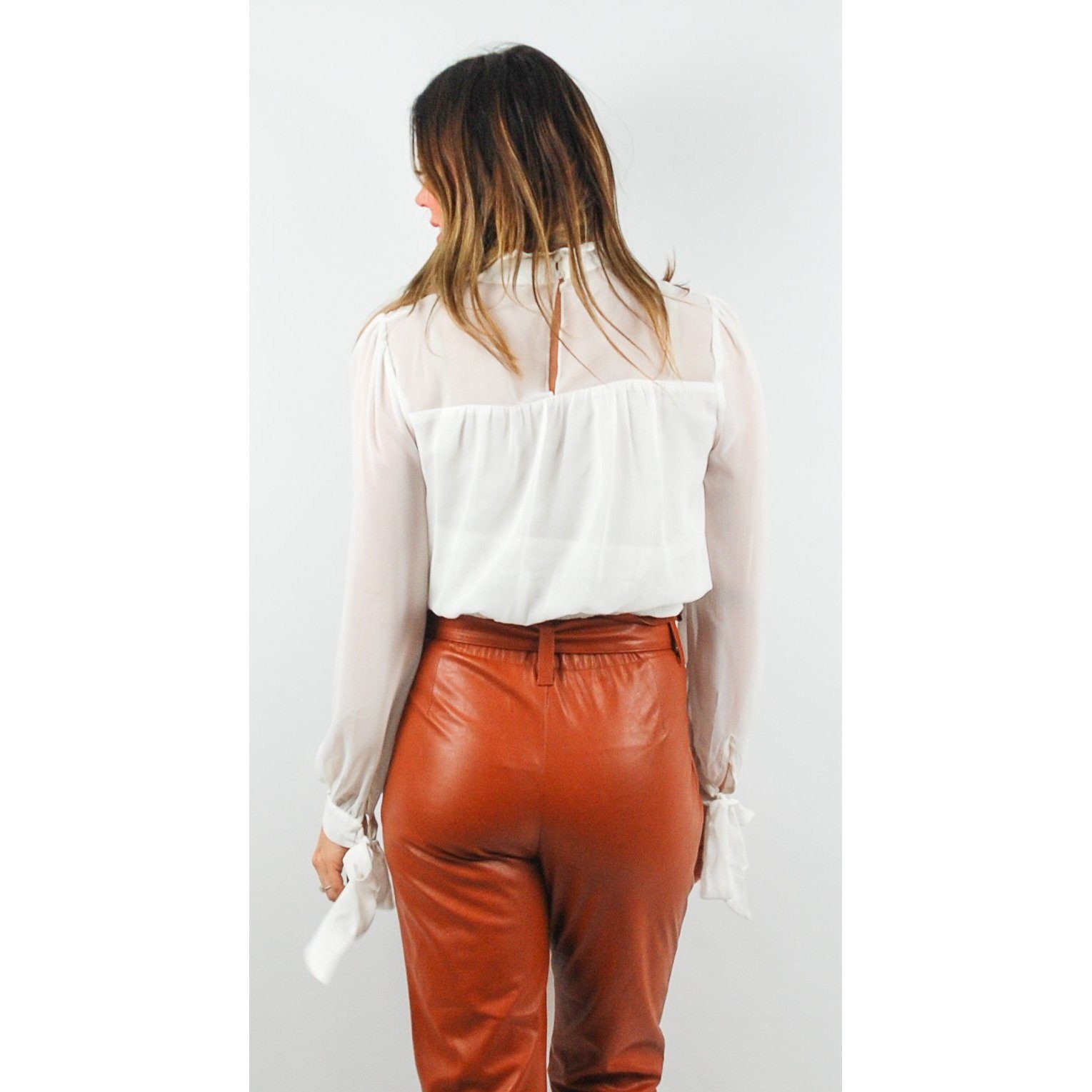 Blusa blanca con pliegues, mangas con lazos en los puños y escote con abertura